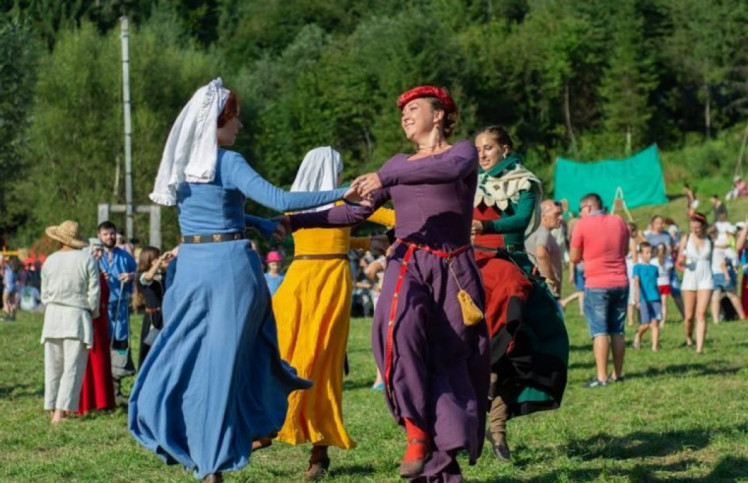 Жінки в середньовічних костюмах танцюють 